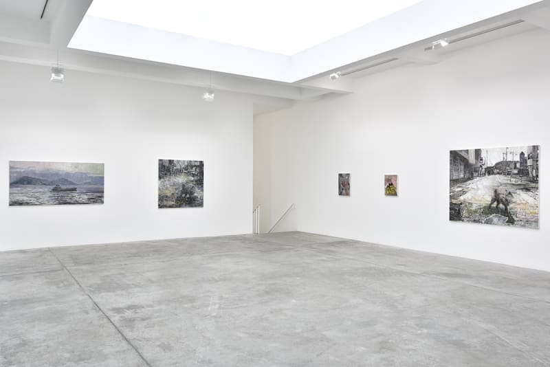 In a large white space, several expressionist oil paintings of various sizes and subjects hang.