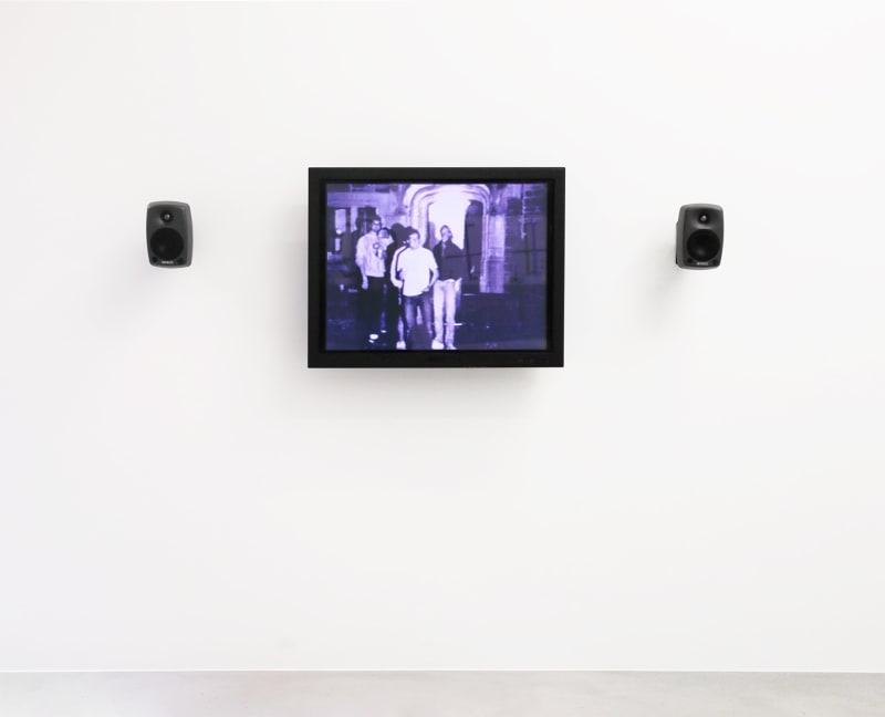 A purple monitor with 2 speakers displays an image of figures gathered outside. 