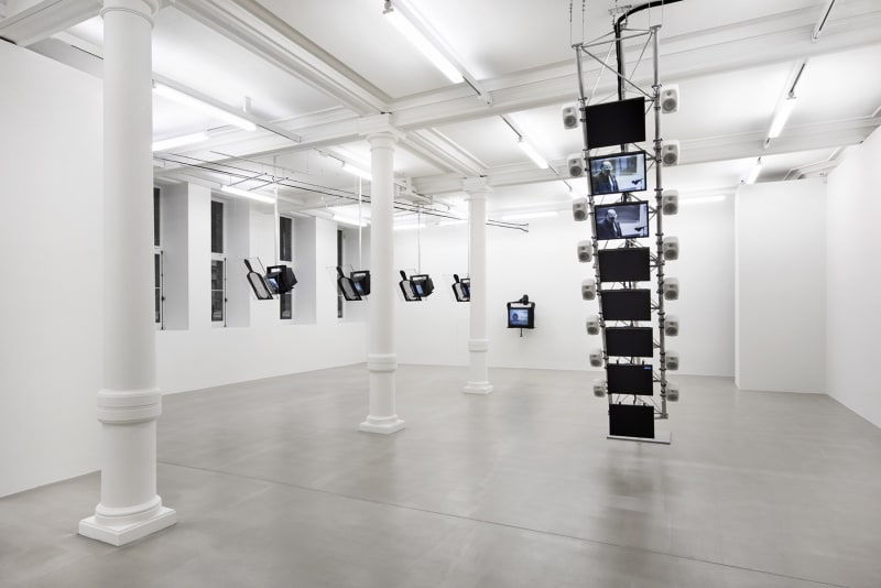 8 flatscreen monitors are stacked vertically from the ceiling; 5 additional T.V.s hang from the ceiling to the left. 