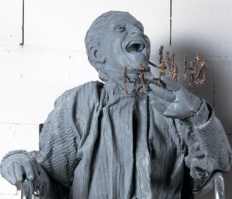 A sculpture of a laughing man holding figurines. 