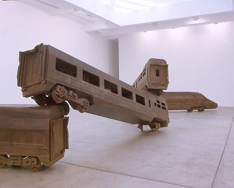A sculpture of 4 train cars stacked on top of each other in a zig zag line. 