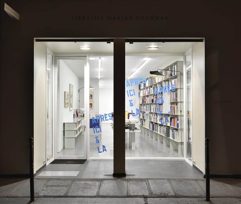 View of the librairie lit up from the interior as seen from the street at night.