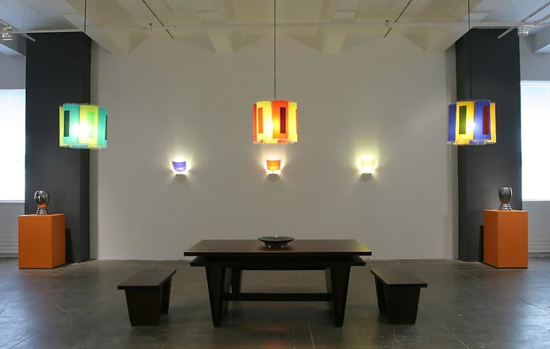 Colored lights hang above a dining room table and orange pedestals.