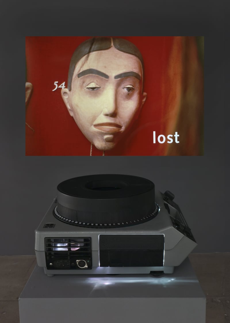 Installation view of Lothar Baumgarten's projection, containing an object with the word "lost" underneath.