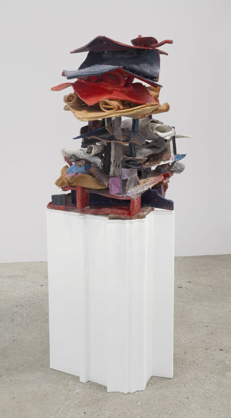 An abstract sculpture sits on a white pedestal.