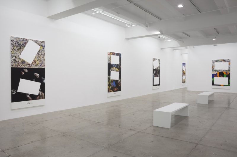5 paintings partially covered with white rectangles hanging in a gallery space with 2 white benches.