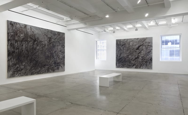 2 abstract paintings hang in a white gallery space with a bench.