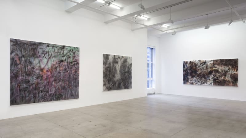 3 abstract paintings hang in a white gallery space with a window.