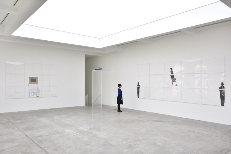 A woman looks at an artwork on the wall, there are various panels displaying a man with a hat.