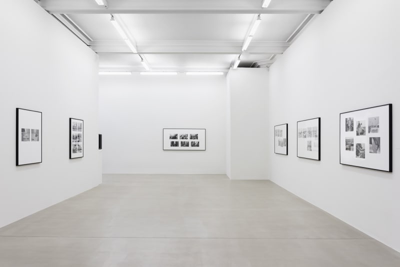 A set of black and white photographs hang on three white walls.