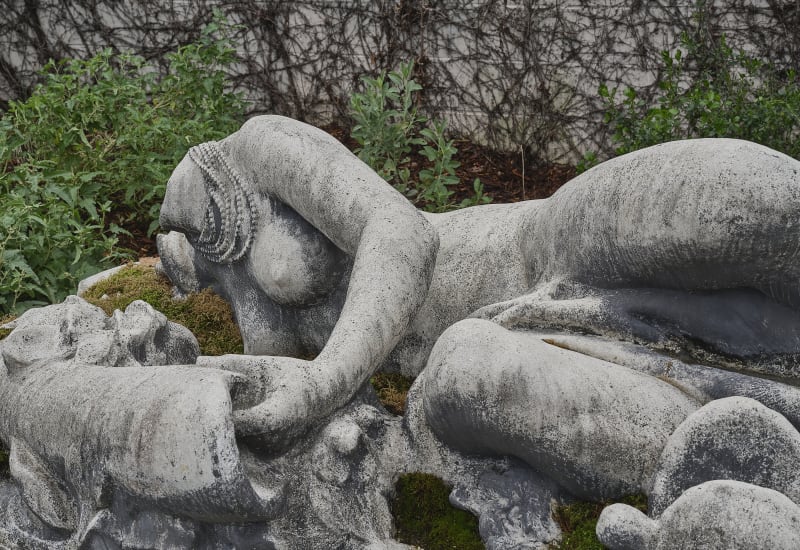Stone sculpture of reclining woman missing head