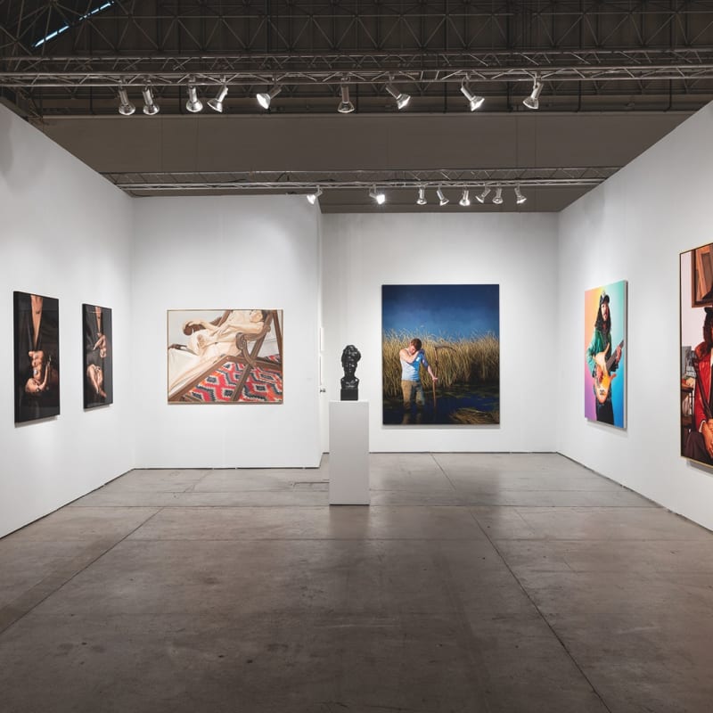 Installation view of gallery's booth at Expo Chicago art fair. The booth shows several figurative paintings hanging on the wall.