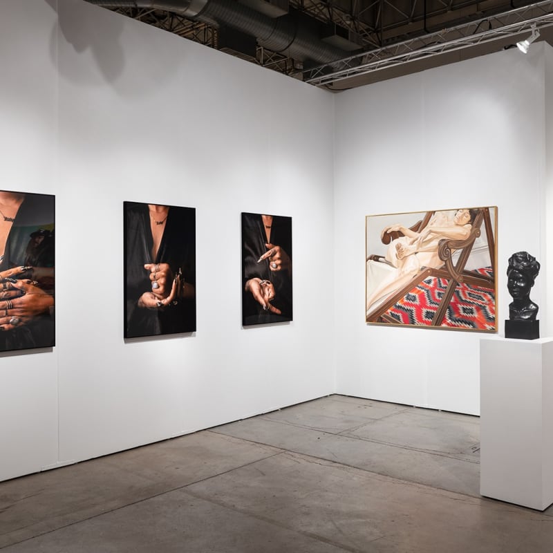 Installation view of gallery's booth at Expo Chicago art fair. The booth shows several figurative paintings and photographs hanging on the wall.