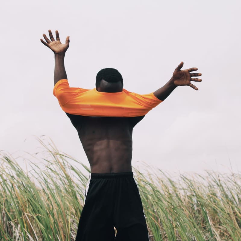 Homme portant un t-shirt orange et avec les bras écartés photographié par le ghanéen Nana Yaw Oduro 
