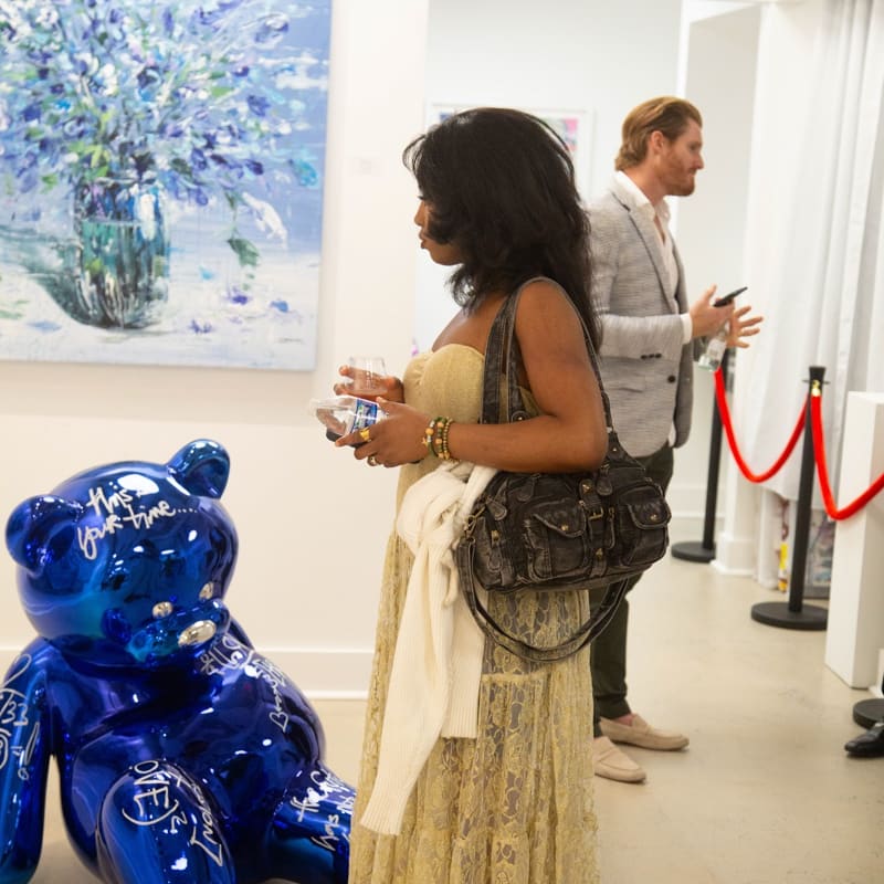 People staring at Eric Alfaro's paintings displayed in Carousel Fine Art's Buckhead Village location during the Eric Alfaro exhibition "Spring Reverie."