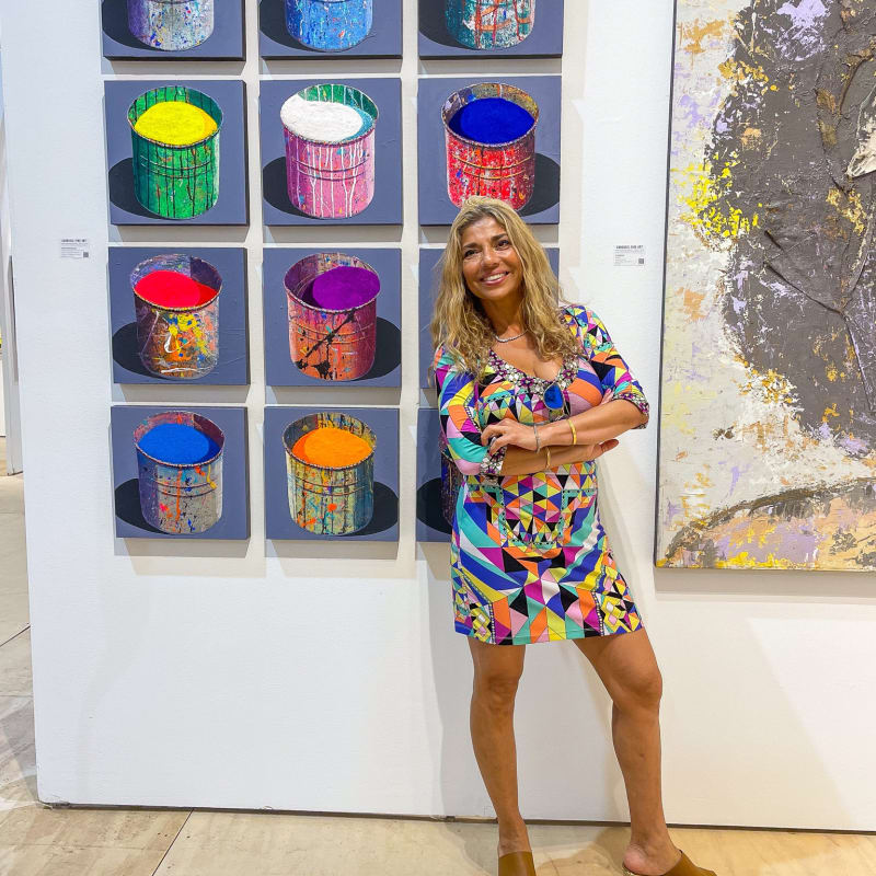 Woman posing in front of paintings displayed at Carousel Fine Art's booth at the Palm Beach Show art fair, 2022.