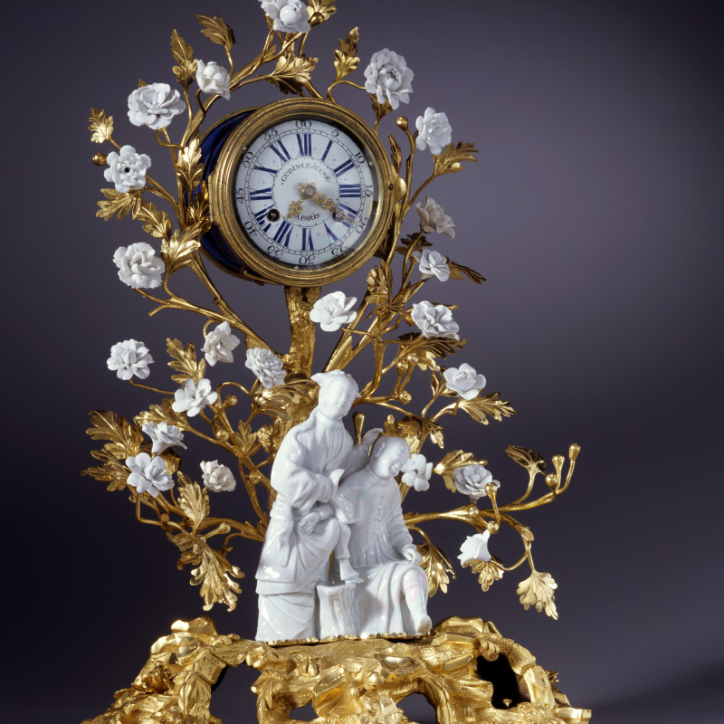 Gudin Le Jeune - A Louis XV mantel clock of eight day duration by Gudin Le Jeune, The gilt bronze: Paris; the figurines: Dehua China; the porcelain flowers: probably Vincennes, date circa 1740-50
