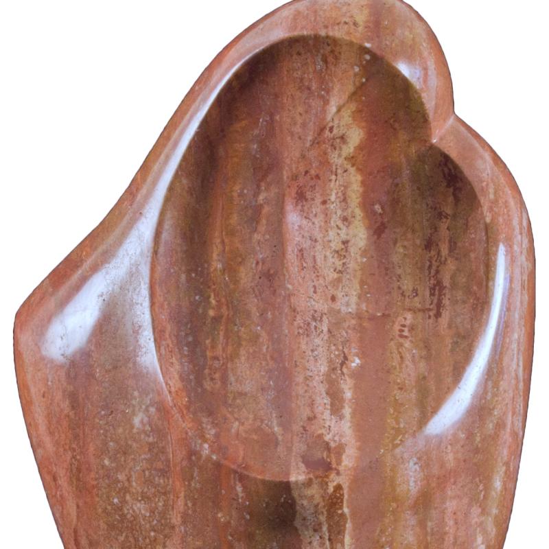An abstract ovoid carving in reddish stone representing a mother and child.