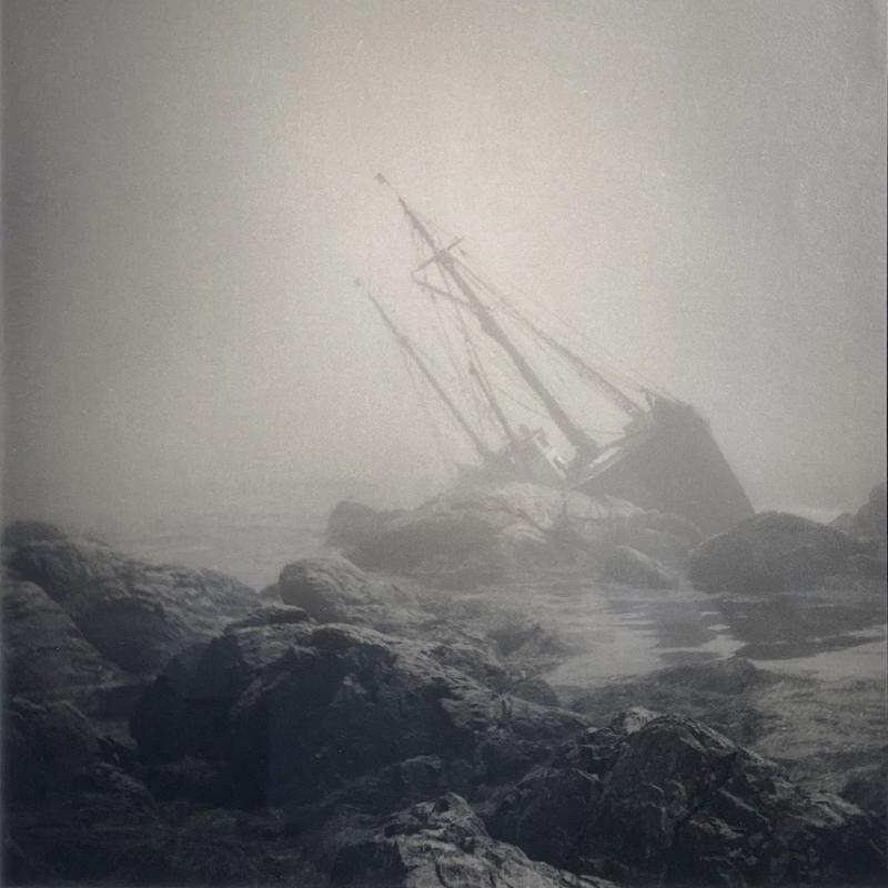P photograph of a wrecked ship on a rocky outcropping in fog