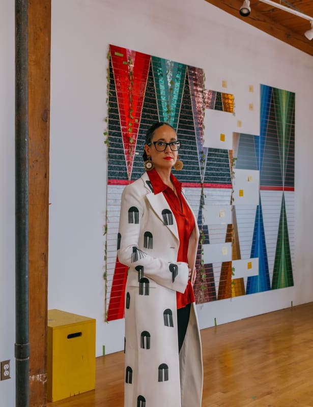 Dyani White Hawk with "Wopila | Lineage II" (a work in progress). Photographed in Minneapolis, December 2022. Styled by Christina Holevas. White Hawk wears a Proenza Schouler coat; Vince blouse; her own pants, glasses, and jewelry. Hair and makeup by Peter Phung.