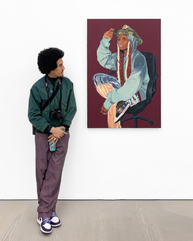Image shows artist Wesley George standing next to his painting in a gallery
