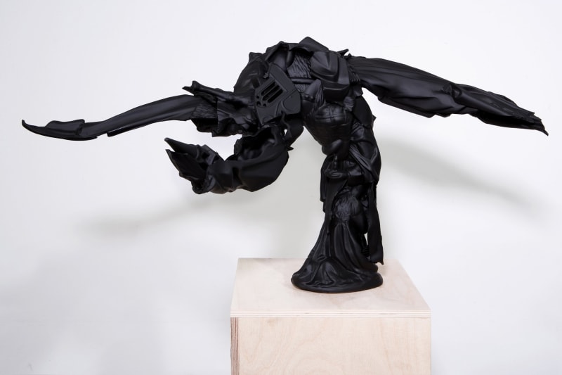 Black abstract sculpture sitting on wood platform