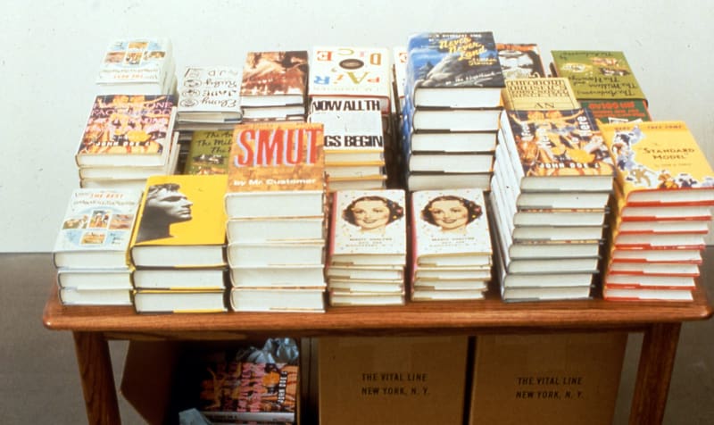Stacks of hard and soft-cover books displayed on a wooden table