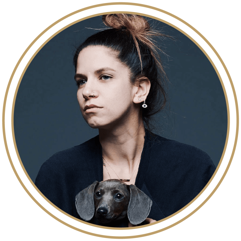 Photo of the artist Caitlin Cronenberg holding a little black dog