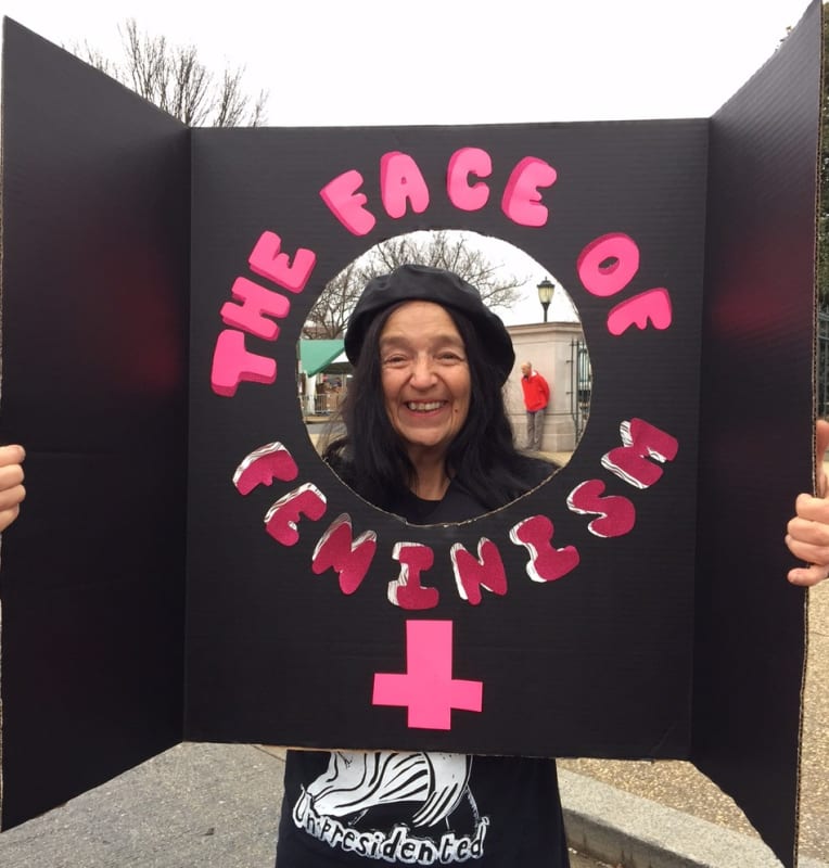 Photograph of the artist holding up a protest sign that reads "The Face of Feminism" at the Women's March, Washington D.C., January 2017