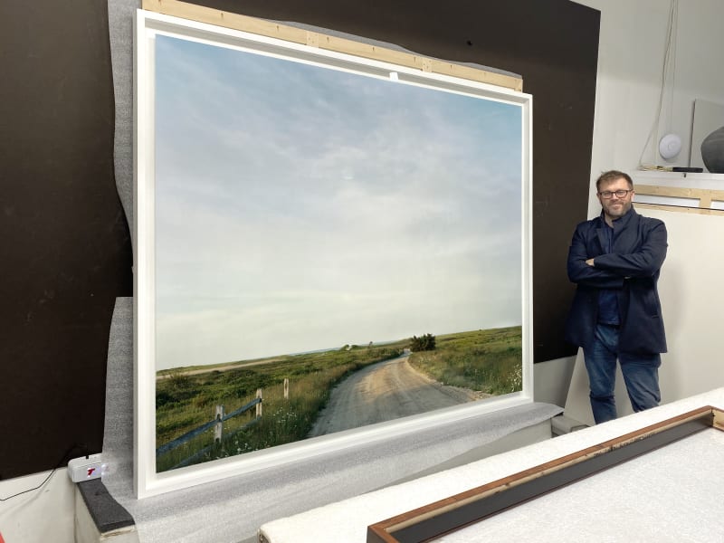 Gaillard standing next to a finished 74 x 86 inch piece with the mounted piece floated within the frame