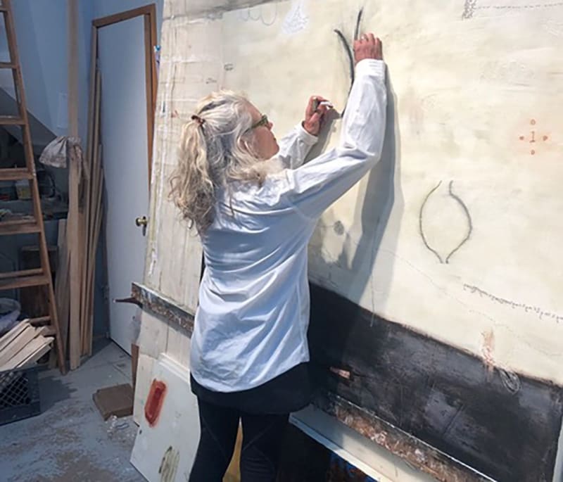 danae anderson standing in her studio and working on a painting