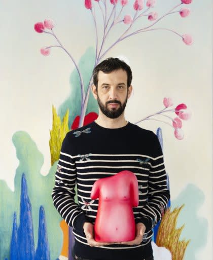 Nicolas Party holding a pink torso sculpture against a colorful floral background.
