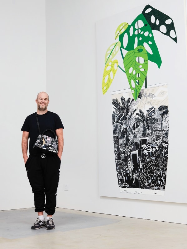 Jonas Wood standing next to a large painting of a potted plant with green leaves and intricate black and white patterns.
