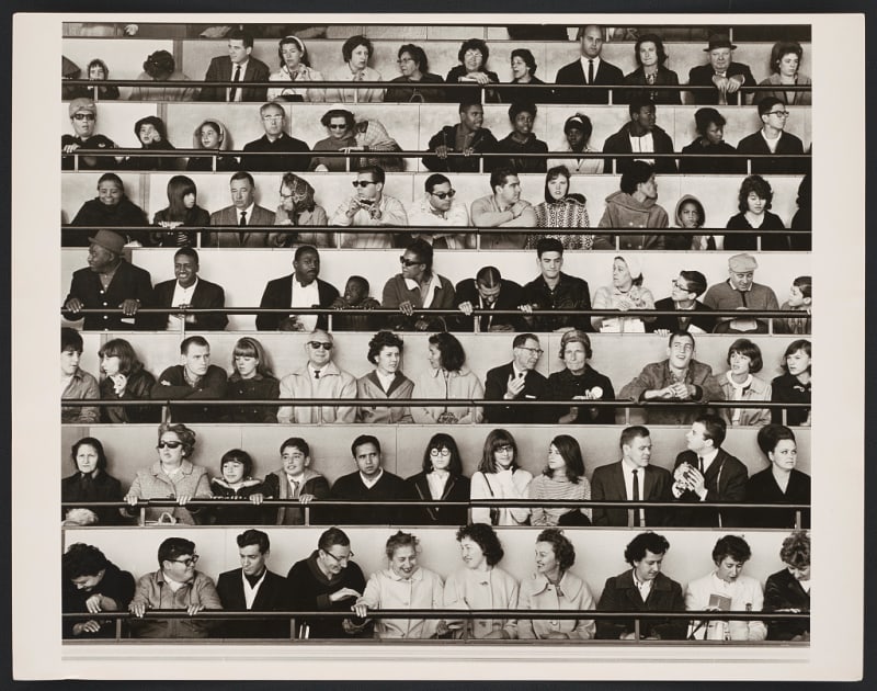 Black and White photograph of men, women and children at the "People Wall," audience seating at the Ovoid Theater, IBM pavilion during 1964-1965 New York World's Fair.