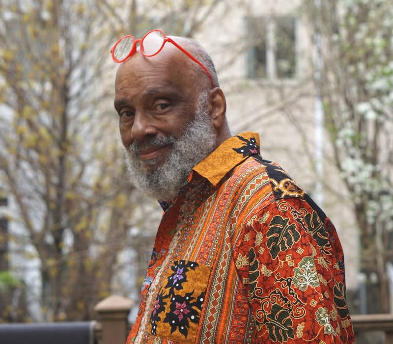 Photograph of artist Danny Simmons posing outdoors in a patterned orange shirt