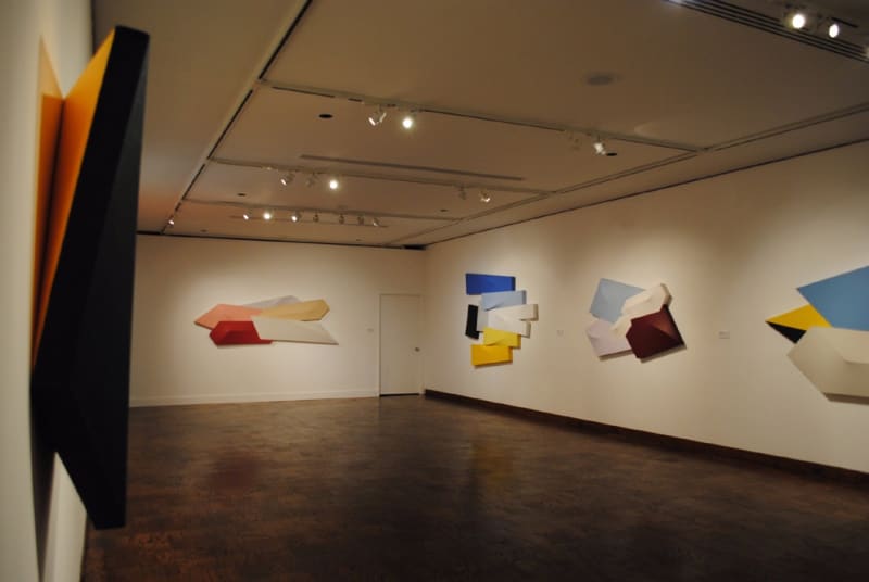 Installation view of colorful tridimensional shaped paintings in a museum setting