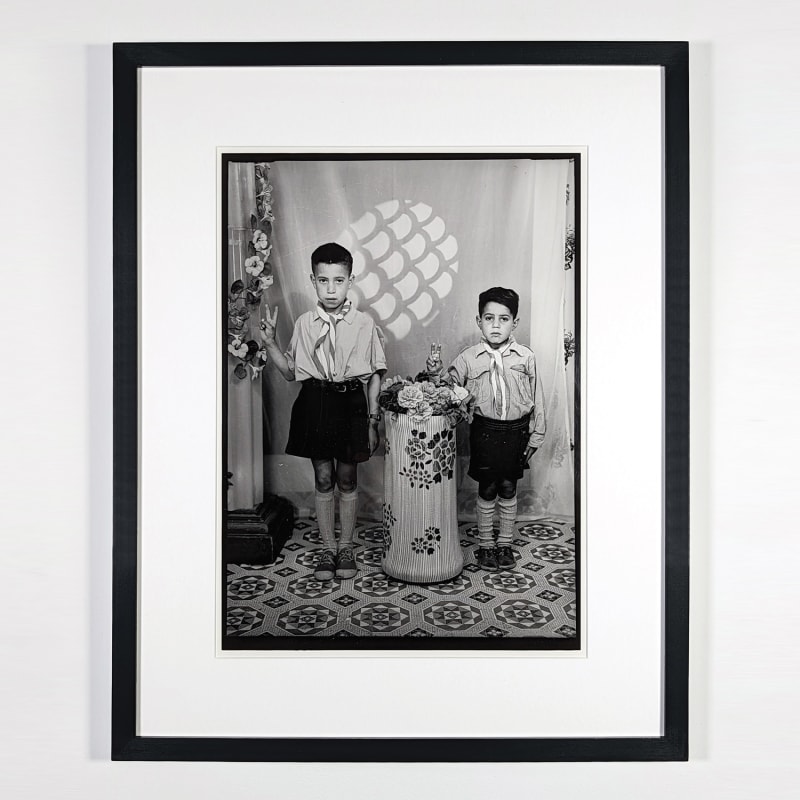 Black and white photograph of two children posing in a photo studio in Ain Beida, Algeria