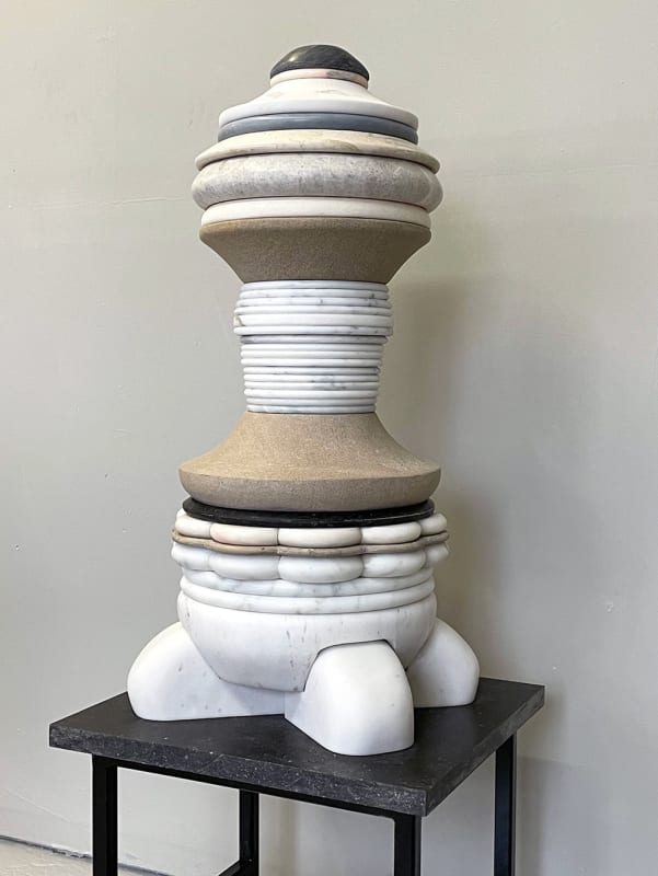 A sculpture by Don Porcaro comprising stacked layers of marble and limestone in an interior setting