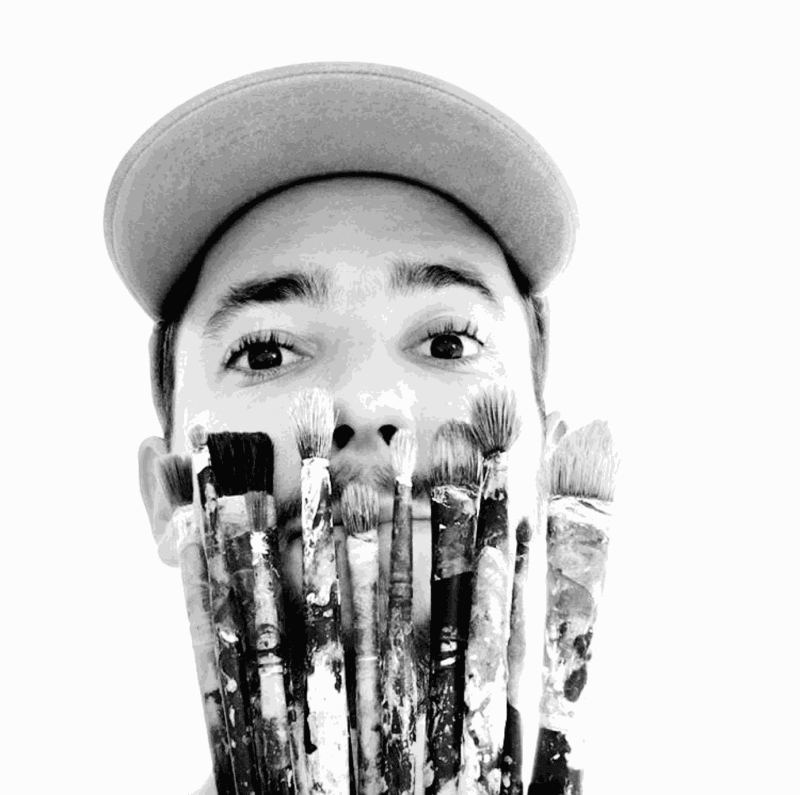 Artist Chance Cooper posing with paintbrushes.