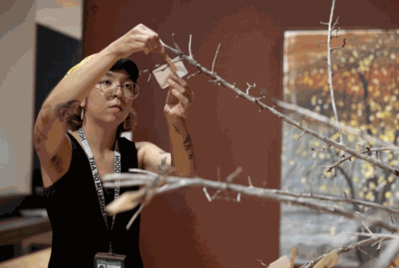 Hood Museum staff attach a visitor’s poem to a dead apple tree, The Emissary, bringing it back to life.