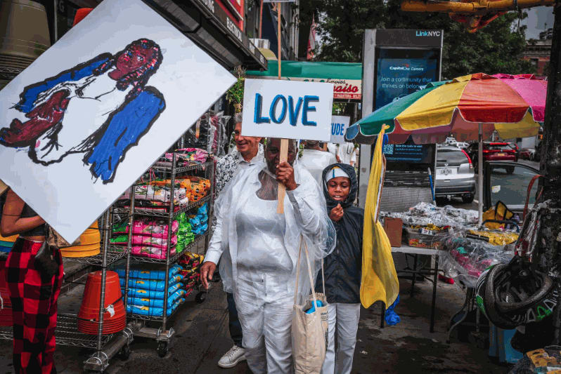 Members of the procession proceeded down Third Avenue in Harlem, carrying signs that said, “Love” and “Unity.” Credit: Graham Dickie/The New York Times