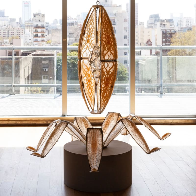 Luis Enrique Zela-Koort, Bulb of Latent Desires, 2023, hanging sculpture: resin and fiberglass panels, pigments, steel frames, bolts and chain segments, 3D-printed PLA matrix, thread, blown-glass helix with encapsulated “primordial soup,” 200 × 150 × 150 cm