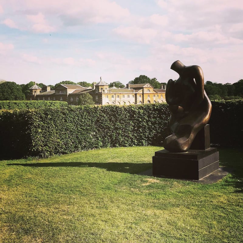 Mother and Child by Henry Moore with our venue - the stables at Houghton Hall in the background