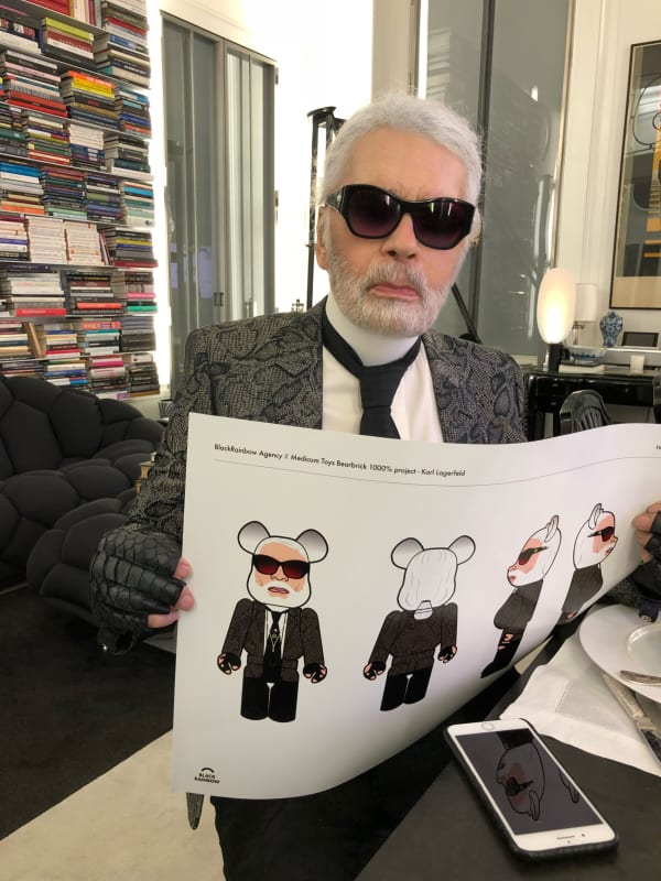 An image of Karl Lagerfeld holding a mockup of the Bearbrick in his likeness.
