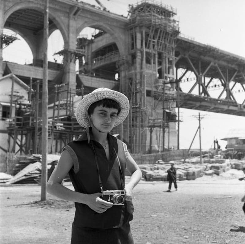 Agnès Varda avec son appareil photo Leica devant le pont de Wuhan en construction, Chine, 1957. Archives Agnès Varda. © Succession Agnès Varda