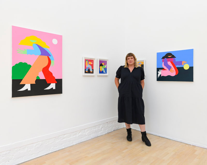 photo of marbie standing in front of her paintings