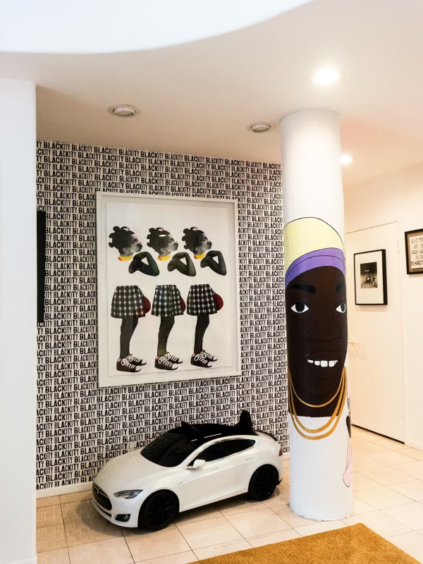 Ron Norsworthy’s “Blackity” wallpaper plays off the patterns in Deborah Roberts’s An Act of Power; a toy Tesla by Radio Flyer is parked next to a Lauren Halsey work; on the door is an untitled photo from Carrie Mae Weems’s “Kitchen Table Series” in Joy Simmons' home.