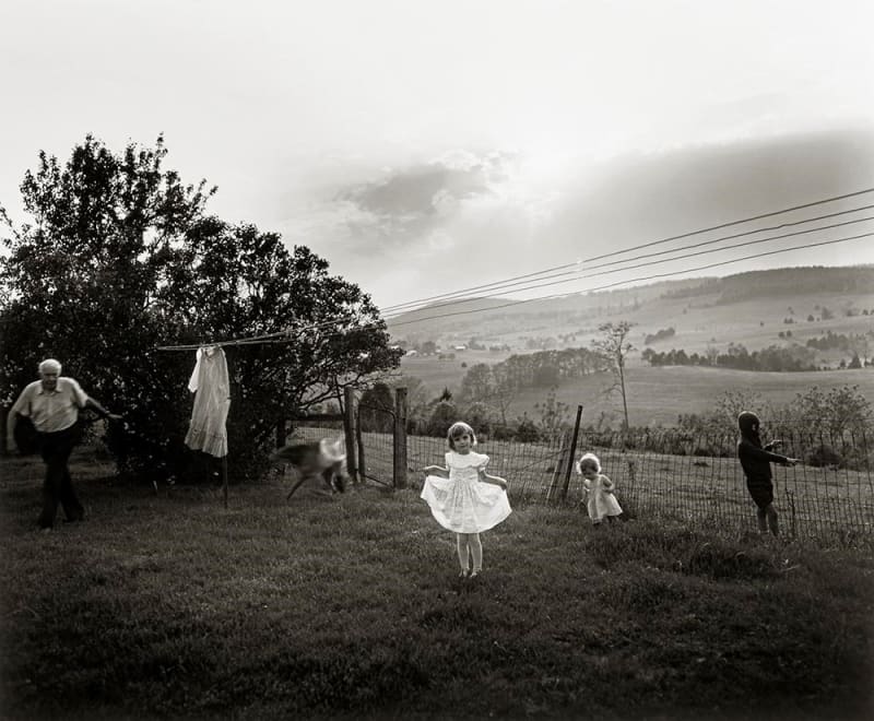Sally Mann Easter Dress A Thousand Crossings at the Museum of Fine Arts Houston, girl in white dress under laundry line with children and farm in background