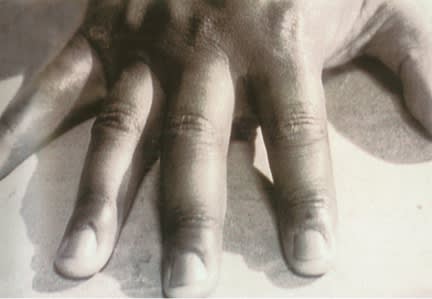 Up close sepia image of a hand, with an emphasis on three of the fingers,