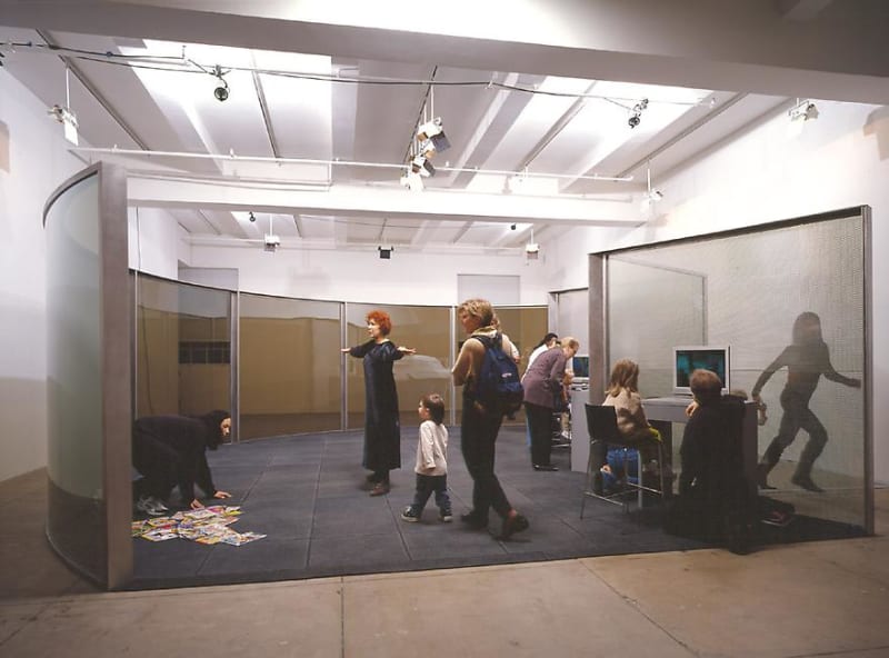 Figures convening in Dan Graham installation of curved glass screens.